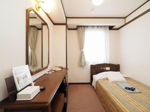 a bedroom with a bed and a desk with a mirror at Hotel Terminal Inn in Niigata