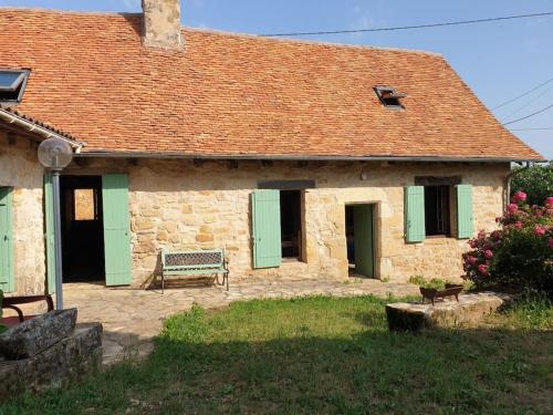 a stone house with green shutters and a bench at Charmante maison périgourdine in Granges-dʼAns