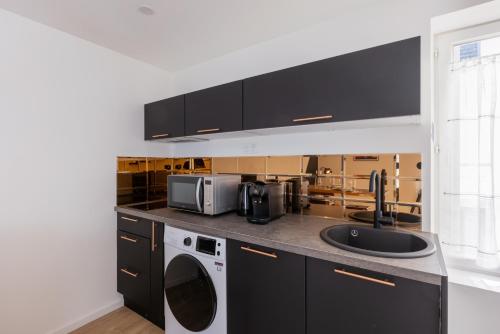une cuisine avec un évier et un micro-ondes dans l'établissement La Symphonie - Cosy - Climatisation - Proche Gare, à Montluçon