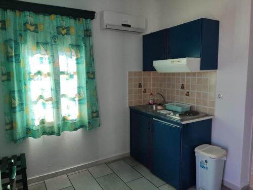 a small kitchen with blue cabinets and a window at Dina's Diamond in Agios Prokopios