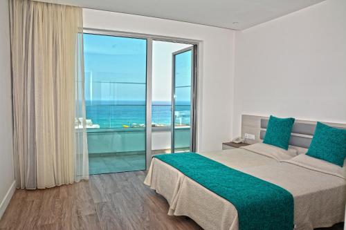 a bedroom with a large bed and a large window at Melini Hotel Suites in Protaras