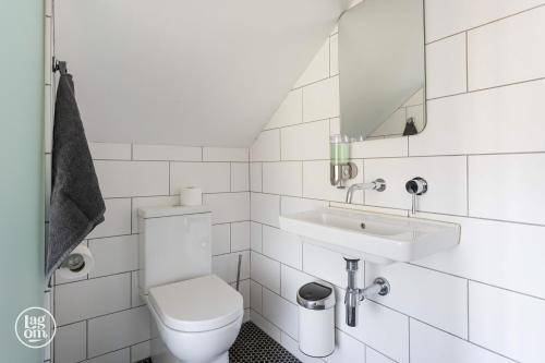 a white bathroom with a toilet and a sink at Riders Lodge - STAY LAGOM in Ballycastle