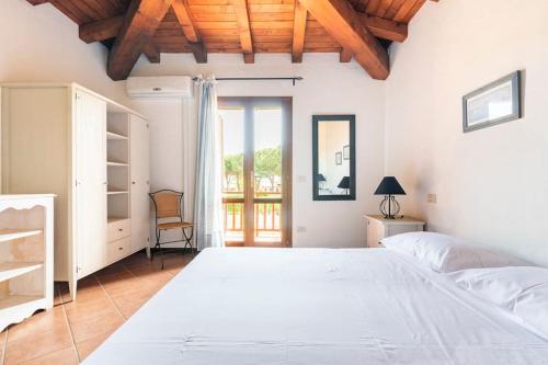 una camera da letto con un grande letto bianco e una finestra di Residenze Coda Cavallo - Punta Aldia - Casa delle Sughere a Puntaldia