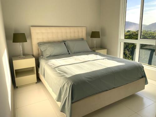 a bedroom with a bed with two night stands and a window at Apartamento 3 suítes Camburi in Camburi