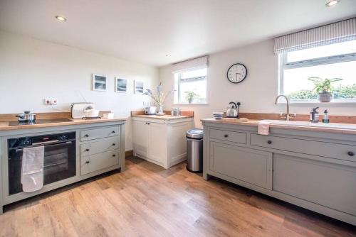 a large kitchen with wooden floors and white cabinets at Gardiners Cottage Barn in Eye