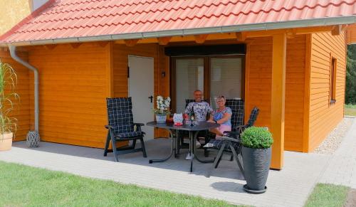 ハッセルフェルデにあるPremium-Plus-Ferienhaus Skadi Iの家の外のテーブルに座る男女