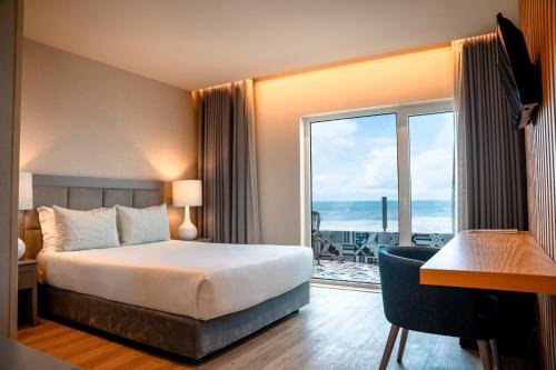 a hotel room with a bed and a view of the ocean at Hotel Cristal Vieira Praia & SPA in Praia da Vieira