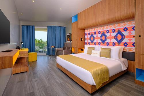 a hotel room with a large bed and a desk at Zone By The Park Gopalpur in Gopālpur