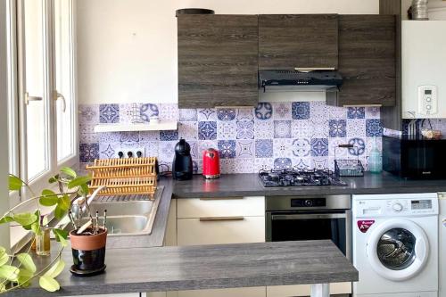 une cuisine avec une cuisinière et une machine à laver dans l'établissement Joli T2 en centre-ville Lorient avec balcon cosy, à Lorient