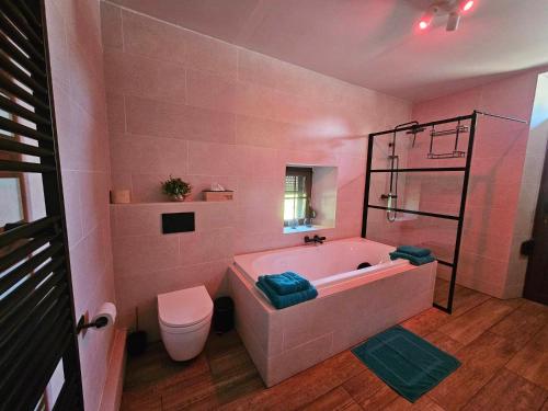 a pink bathroom with a tub and a toilet at Ferme La Joye in Houffalize