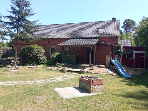 una casa con parque infantil y un tobogán en el patio en Ferienwohnung Schaeferhof, die Natur vor der Haustüre, en Cottbus