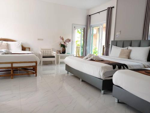 a white bedroom with two beds and a table at Panisara Pool Villa Resort Huahin in Hua Hin