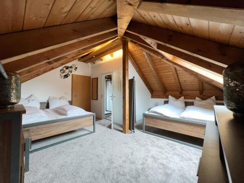 two beds in a room with wooden ceilings at Haus Uhlennest in Ühlingen-Birkendorf