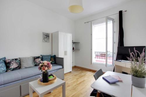ein Wohnzimmer mit einem Sofa und einem Tisch in der Unterkunft Amazing studio 2P near Paris et La Défense in Levallois-Perret
