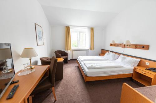 a hotel room with a bed and a desk at Sonnenhotel Hoher Hahn in Schwarzenberg