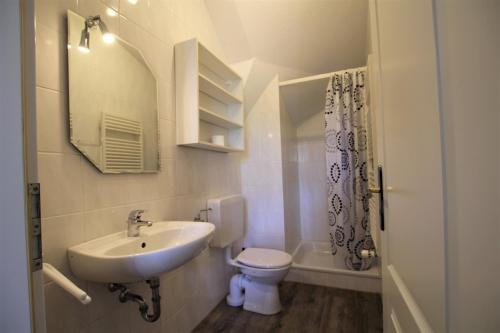 Un baño con lavabo, inodoro y espejo. en Untere Teichwohnung, en Fehmarn