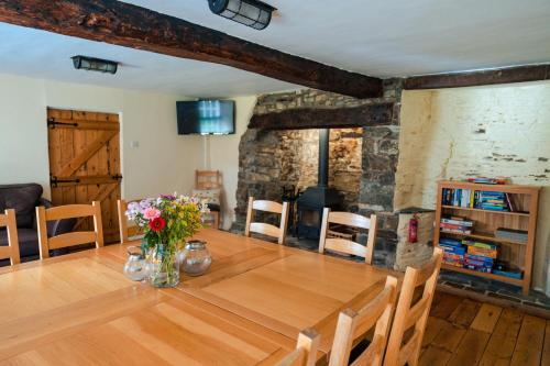 a dining room with a wooden table with flowers on it at Poyers Farmhouse in Wrafton