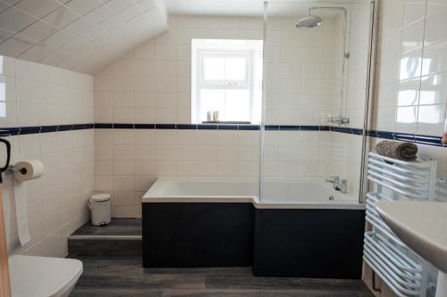 a bathroom with a tub and a toilet and a sink at Poyers Farmhouse in Wrafton