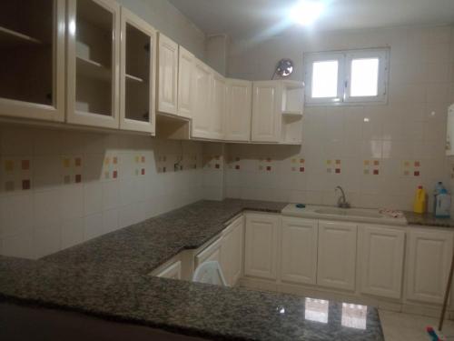 a kitchen with white cabinets and a sink and a window at DarAttiaKelibia in Kelibia