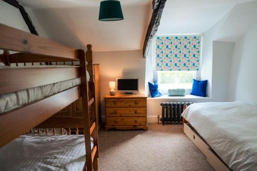 a bedroom with two bunk beds and a window at Poyers Farmhouse in Wrafton