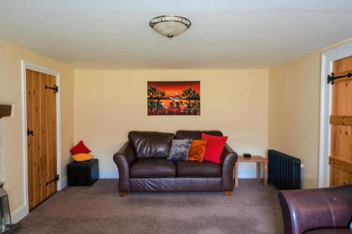 a living room with a brown leather couch at Poyers Farmhouse in Wrafton