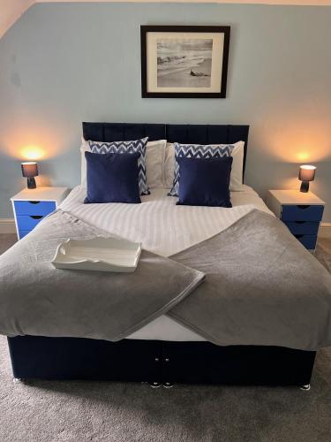 a bedroom with a large bed with blue pillows at Poyers Farmhouse in Wrafton