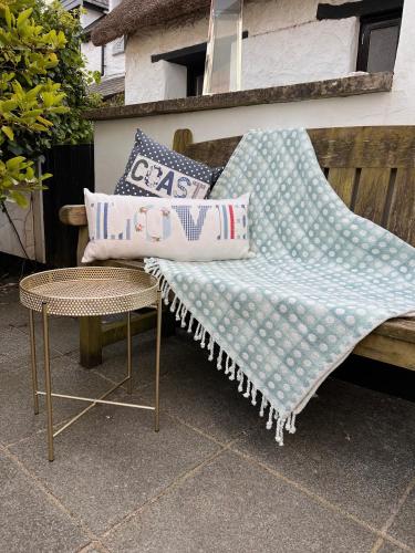 a bench with pillows on it next to a table at Poyers Farmhouse in Wrafton