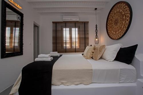 een slaapkamer met een groot bed met witte lakens en kussens bij Nur Mykonian Suites in Mykonos-stad