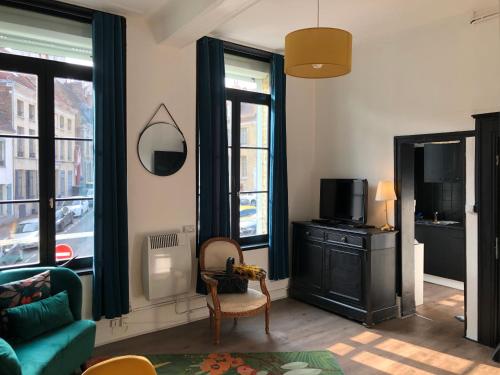 Una sala de estar con un sofá y un televisor y ventanas. en La clef Sithieu, en Saint-Omer