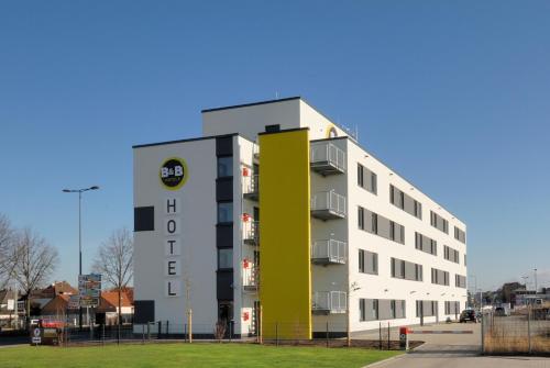 ein weißes Gebäude mit einem gelben Schild darauf in der Unterkunft B&B Hotel Paderborn in Paderborn