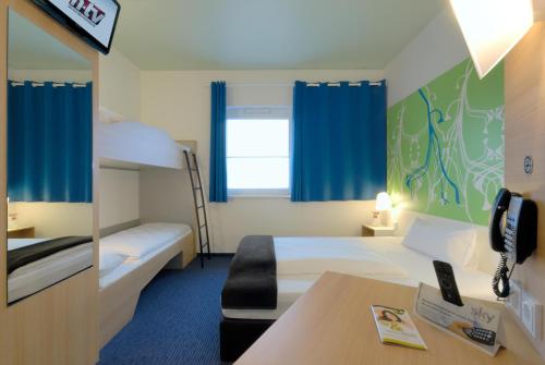 a hotel room with two beds and a desk at B&B Hotel Paderborn in Paderborn