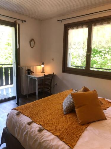 um quarto com uma cama, uma mesa e janelas em Hôtel la Kinkerne em Morzine