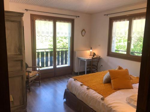 a bedroom with a bed and a desk and windows at Hôtel la Kinkerne in Morzine