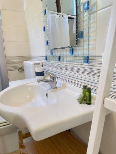 bagno con lavandino bianco e specchio di Il Terrazzo - Galatea casa vacanze a Gagliano del Capo