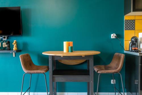 una mesa y 2 sillas en una habitación con una pared azul en Le Studio Enchanté - Vue Magique de Montrichard, en Montrichard