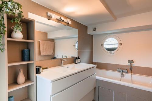 La salle de bains est pourvue d'un lavabo blanc et d'une baignoire. dans l'établissement Péniche de prestige à Namur avec vue sur la Citadelle - A l'Abordage - By Voyages Copine, à Namur