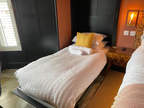 a large bed with white sheets and yellow pillows at Craig Walk Suite in Bowness-on-Windermere