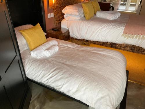 a bedroom with two beds with white sheets and yellow pillows at Craig Walk Suite in Bowness-on-Windermere