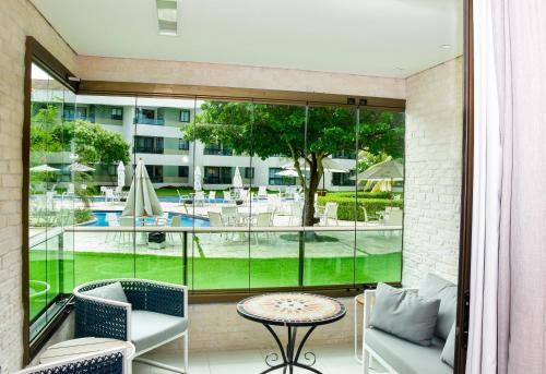 a balcony with a table and chairs and a view of a pool at Luxo à Beira-Mar - Flat 2 Quartos no Carneiros Beach Resort in Praia dos Carneiros