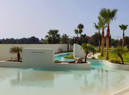 - une piscine avec des palmiers dans un complexe dans l'établissement Kentia golf Playa Granada, à Motril