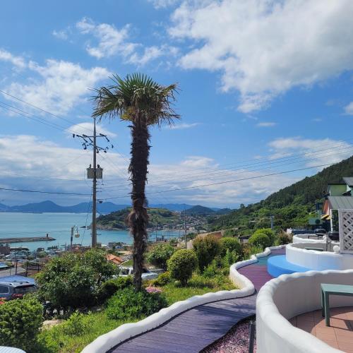 a palm tree on a balcony with a view of the water at Soulmate Pension in Namhae