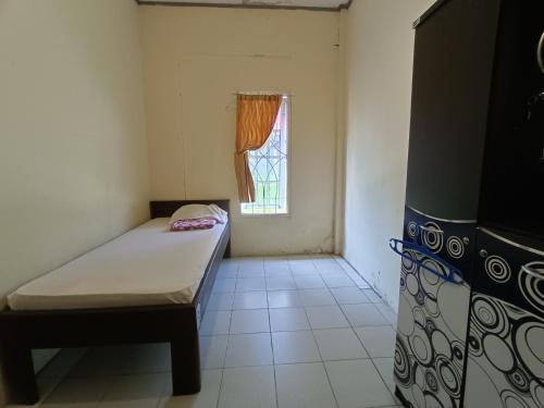 Cette petite chambre comprend un lit et une fenêtre. dans l'établissement OYO 92591 Wisma Pangestu Syariah, à Ujungtanjung