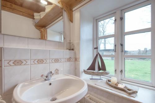 ein Bad mit einem Waschbecken und einem Fenster in der Unterkunft Eider Domizil No1 in Oldenswort