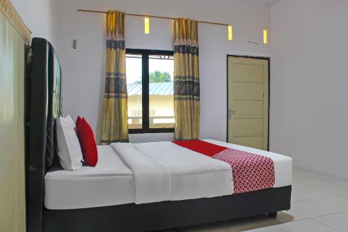 ein Schlafzimmer mit einem Bett und einem großen Fenster in der Unterkunft OYO 92593 Penginapan Sultan Haji 1 in Bandar Lampung