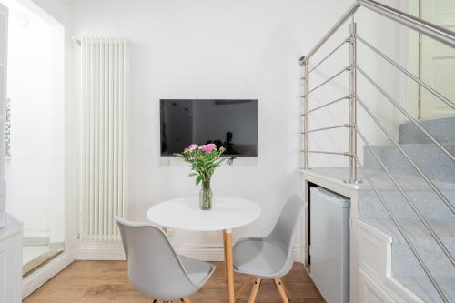 a white table with chairs and a vase of flowers at RELSTAY - Brera District in Milan