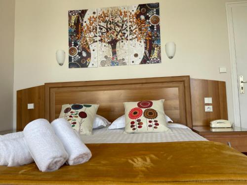 una camera da letto con un letto con cuscini e un dipinto di Le Relais De La Place a Le Faou