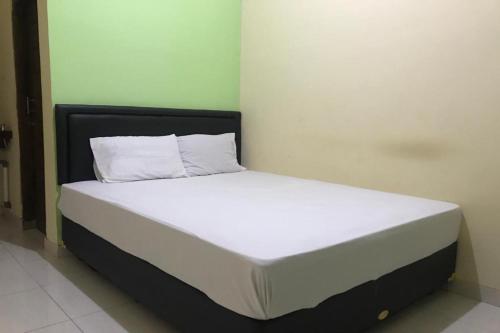 OYO 92608 Penginapan Mc Lodge في لابوان باجو: سرير بشرشف ووسائد بيضاء في الغرفة