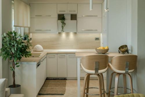Diogia Luxury Apartment في Vanáton: مطبخ مع دواليب بيضاء و كرسيين للبار