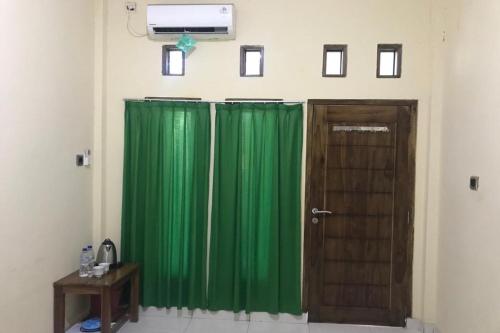 a room with two green curtains and a door at Hotel O Penginapan Mc Lodge in Labuan Bajo