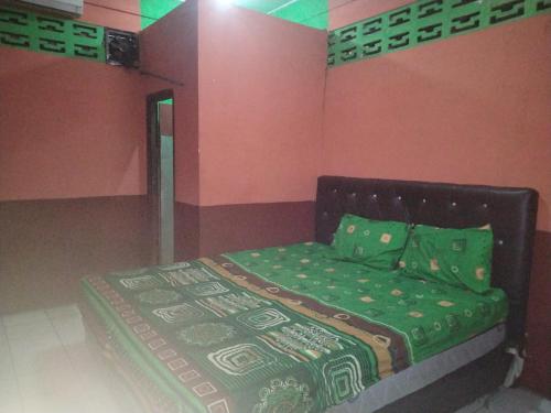 um quarto com uma cama com um edredão verde em SPOT ON 92601 Penginapan Keluarga em Medan